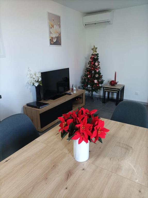 un salon avec un arbre de Noël et une table ornée de fleurs rouges dans l'établissement Maisonnette de Michelle - Peace and quiet, à La Gaude