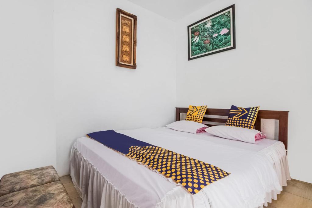 a bedroom with a bed with two pictures on the wall at Hotel O Villa Tirta Melati Syariah in Banjar