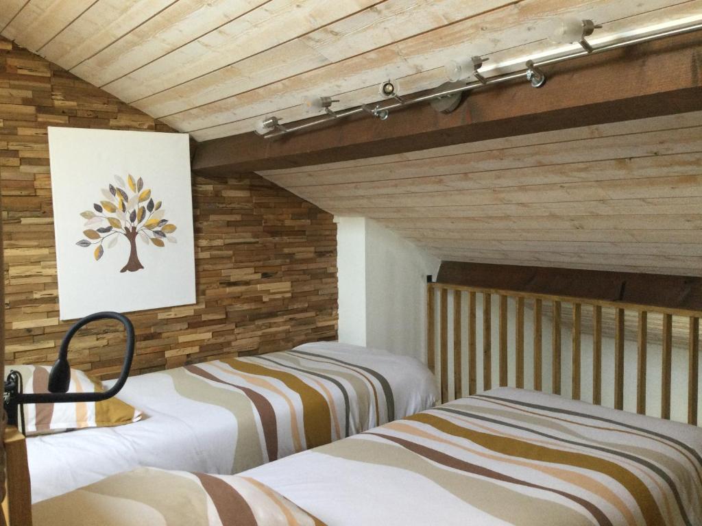 zwei Betten in einem Zimmer mit Holzwänden in der Unterkunft Gite de Belle vue in Semur-en-Brionnais