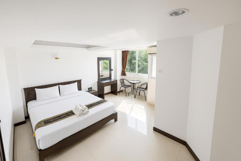 a white bedroom with a bed and a table at Chaweng grand view point in Koh Samui 