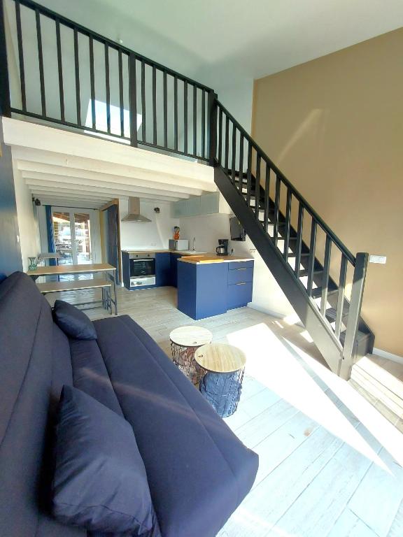 a living room with a couch and a staircase at PLAIN PIED, avec mezzanine et espace extérieur 10min Puy du F in Les Herbiers