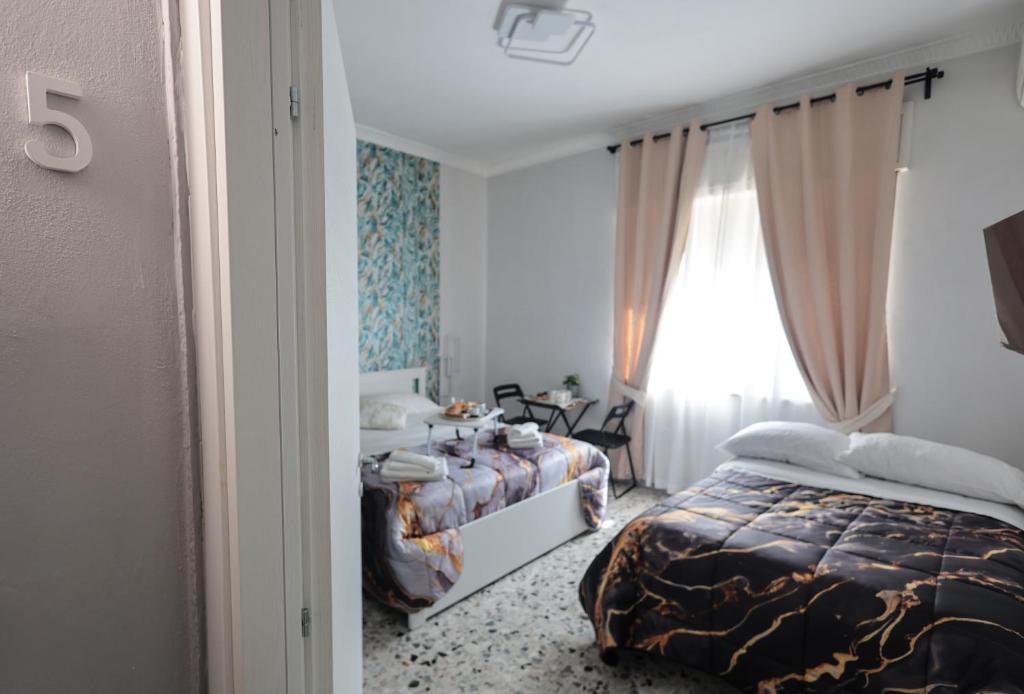 a hotel room with two beds and a window at A cartulina e Napulè Attico con Vista Porto Ascensore Colazione Inclusa Struttura nel cuore autentico di Napoli a 5 minuti dalla Stazione Centrale e dal Centro Storico AC in Naples