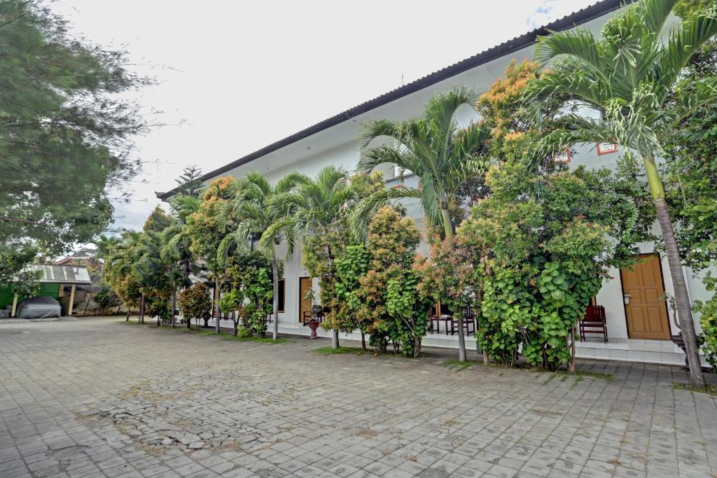 a building with trees and palm trees in front of it at OYO 3096 Hotel Dewi Warsiki Near Gilimanuk Port in Gilimanuk