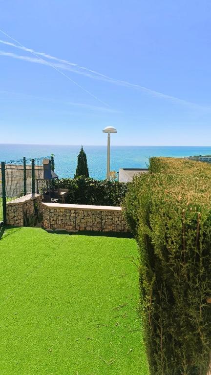 a green yard with the ocean in the background at Ara Bela Duplex con jardin in Peniscola