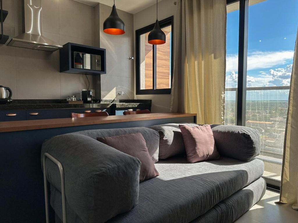 a living room with a couch in front of a kitchen at Apartamento Sunset Residence 1208 in Dourados