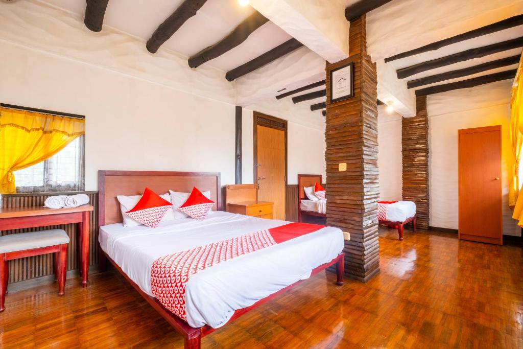 a bedroom with a large bed and a desk at Capital O 2640 Cottage GS Rumah Kayu Syariah in Batureo 1