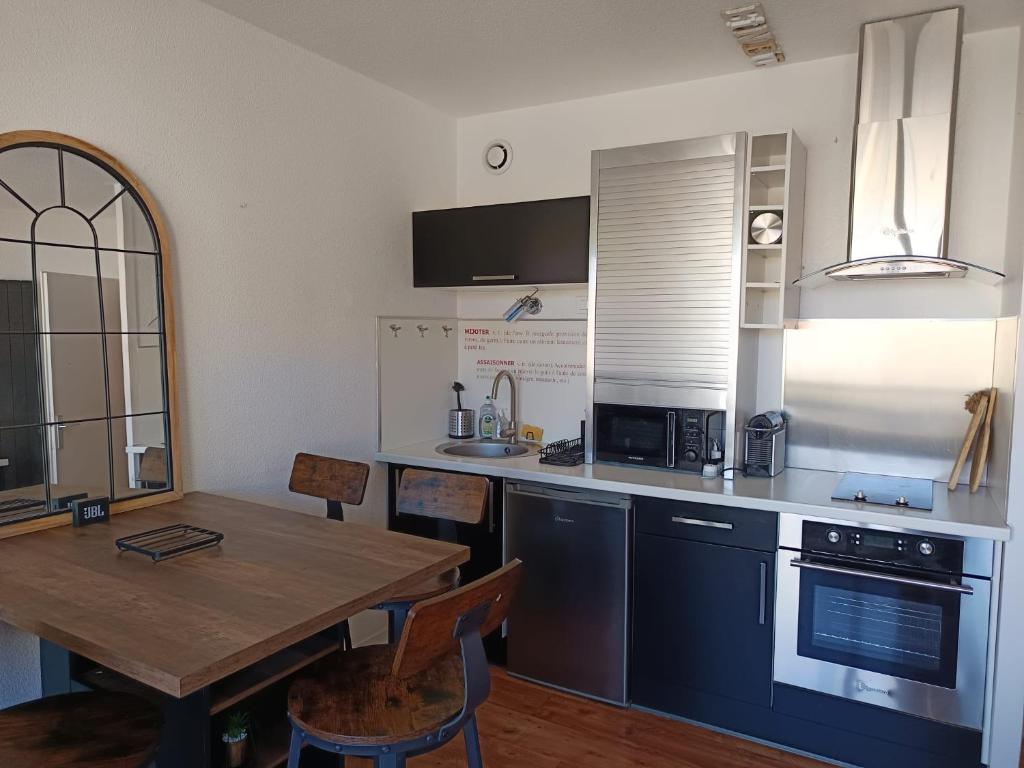 une cuisine avec une table en bois et une table ainsi qu'une salle à manger dans l'établissement Le Cap'Océan, à Mimizan-Plage