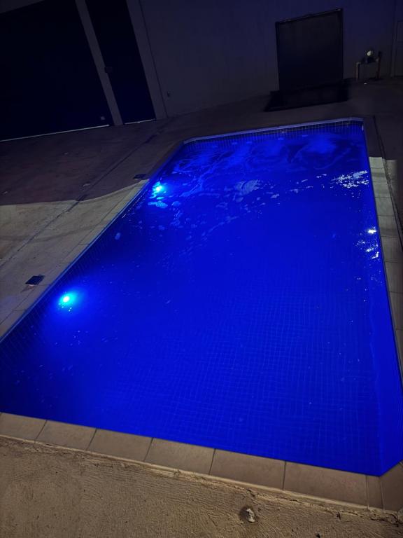 a blue swimming pool with lights on the floor at Maggi Residence in Batatais