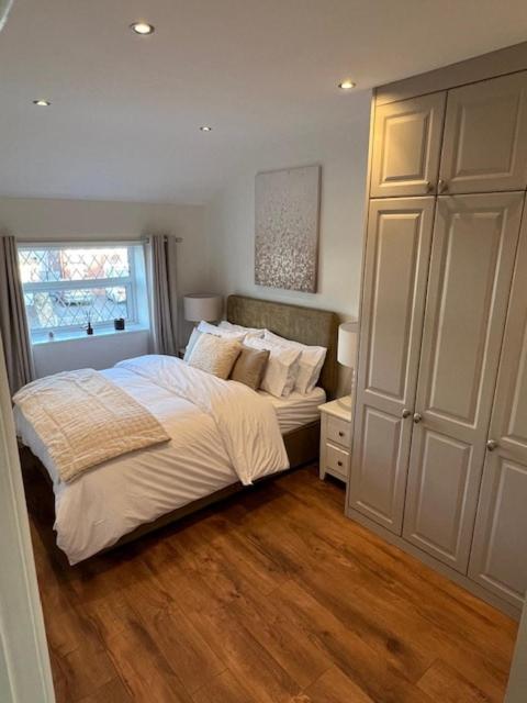 a bedroom with a bed with white sheets and a window at Night Owl Cottage in Rainford