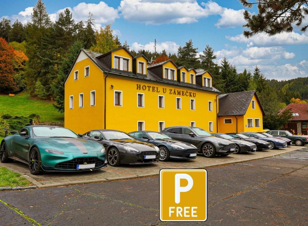 eine Reihe von Autos, die vor einem gelben Gebäude geparkt sind in der Unterkunft Hotel U Zámečku Cihelny in Karlsbad