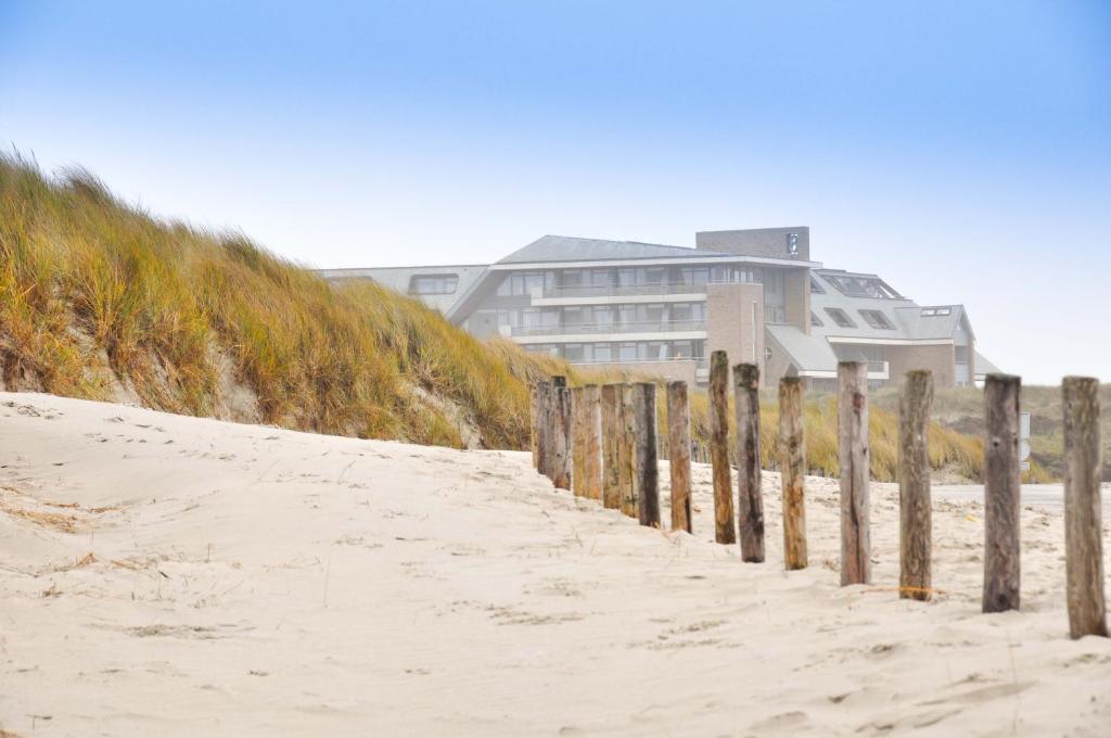 a building on the beach next to a fence at Paal 8 Hotel aan Zee in West aan Zee