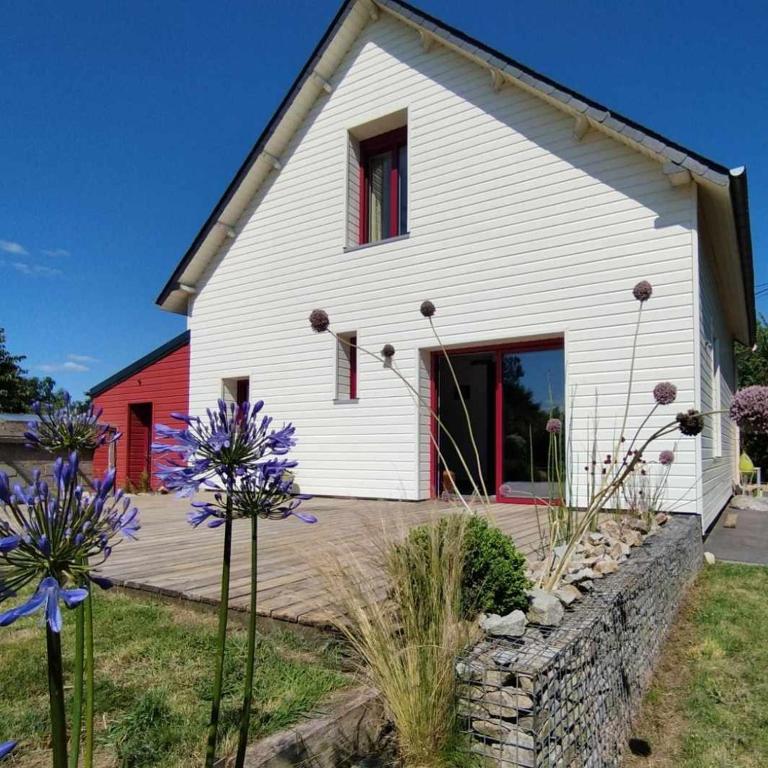 une maison blanche avec des fleurs devant elle dans l'établissement La maison blanche et rouge, à Saint-Hélen