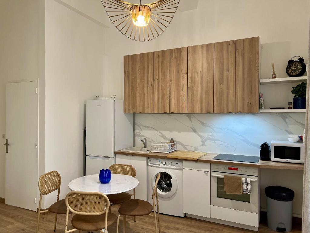 une cuisine avec une table et un réfrigérateur blanc dans l'établissement City Center, Calm & Fresh, à Aix-en-Provence
