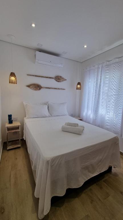 a bedroom with a large white bed with white sheets at Casa da Tieko in Ilhabela