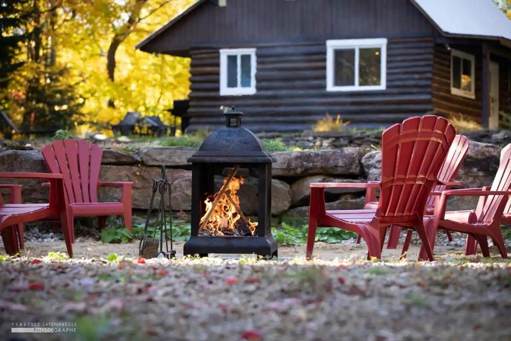 a fire pit in a yard with two red chairs at Chalet Le Merlot in Mandeville