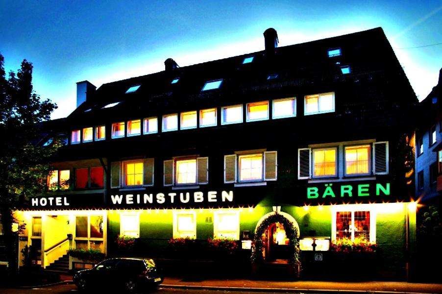 - un bâtiment noir avec des fenêtres éclairées et un bar dans l'établissement Hotel Restaurant Bären, à Freudenstadt