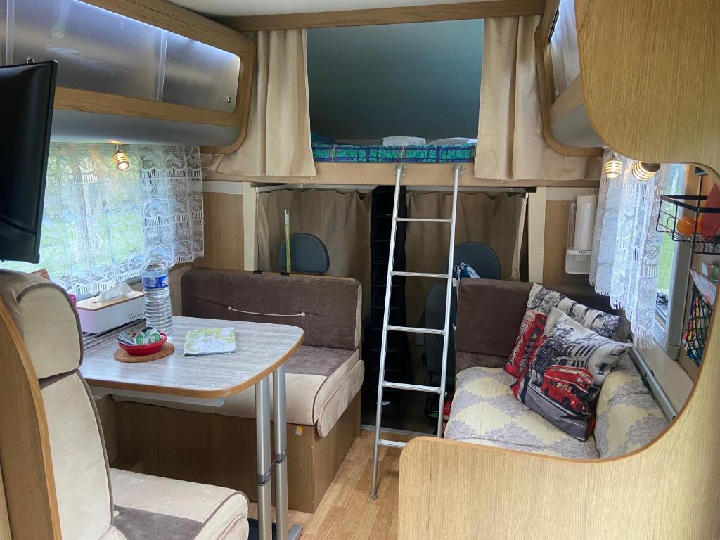 a small room with a table and a dining room at Camping-car au Charme de la Forêt avec jardin Accès à pied Circuit des 25 Bosses in Le Vaudoué
