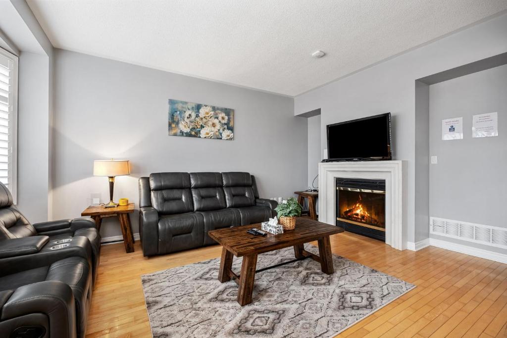Una sala de estar con muebles de cuero y chimenea. en Amazing Spacious house in Center of Richmond hill, en Richmond Hill