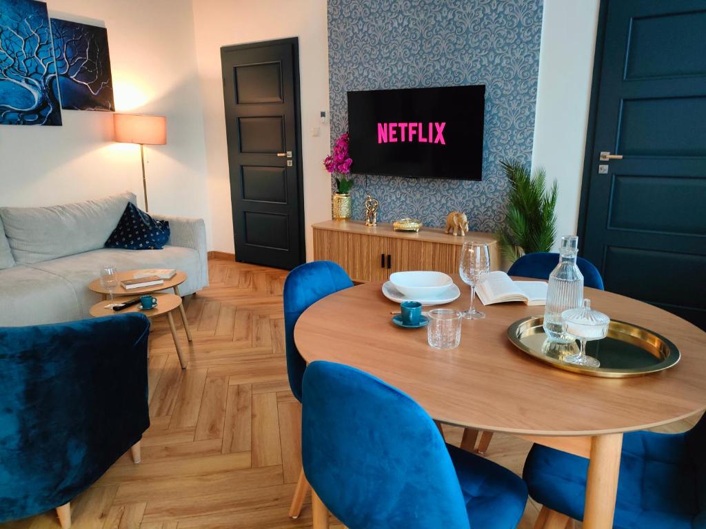 Una sala de estar con una mesa y sillas azules. en Nowe - PERŁA ŚRÓDMIEŚCIA & Free Parking 48m2, en Częstochowa