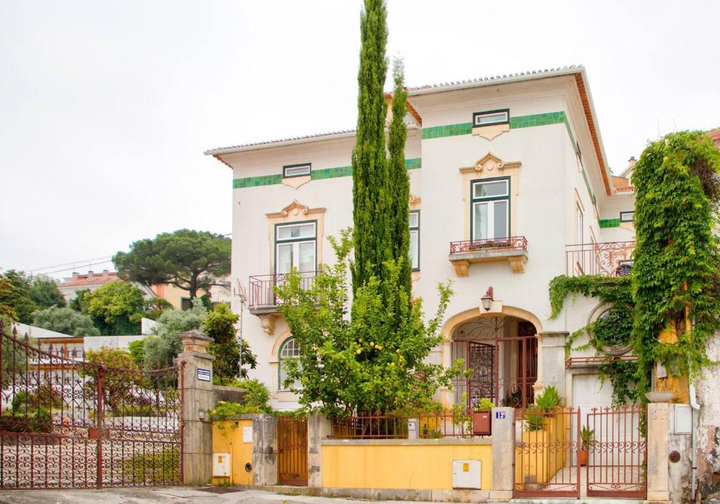a large white house with a fence and trees at Adore Portugal Coimbra Guest House in Coimbra