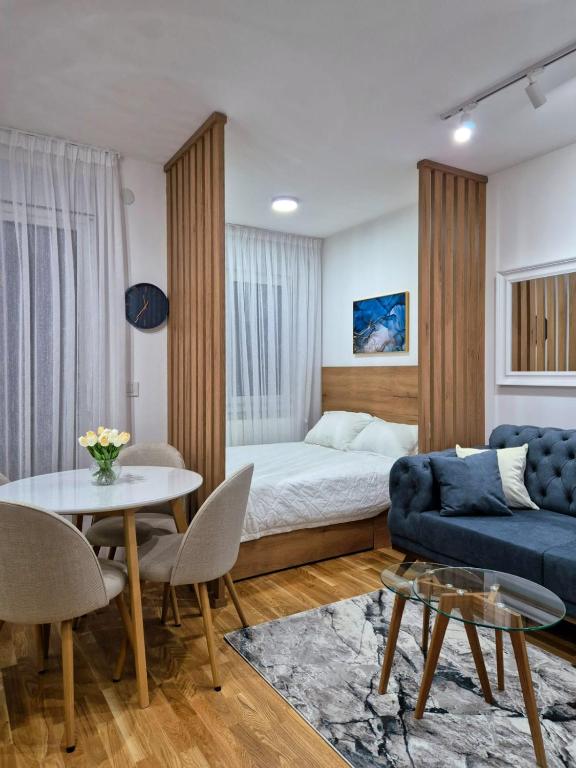 a bedroom with a bed and a table and a couch at Sokolis Apartman in Kragujevac