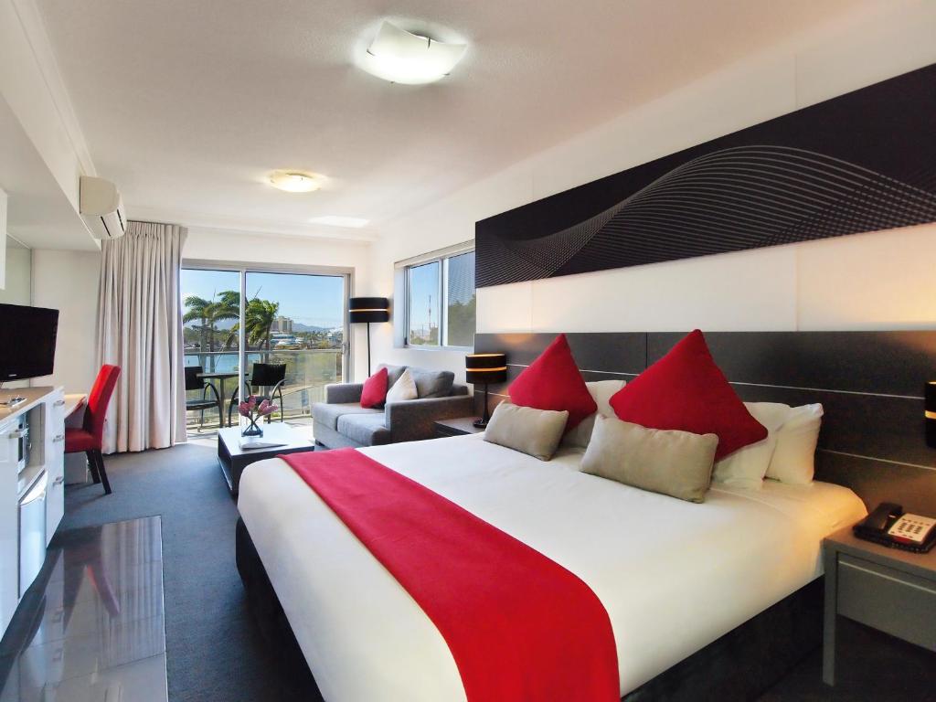 a hotel room with a large bed with red pillows at Oaks Townsville Metropole Hotel in Townsville