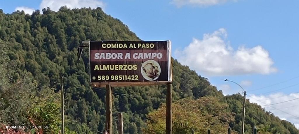 a sign on the side of a road in front of a mountain at Cabañas y piscinas sabor a campo embalse ancoa in Los Rabones