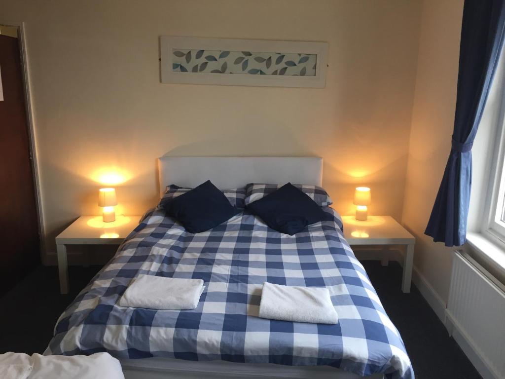 uma cama xadrez azul e branca num quarto em Sailors Return Weymouth em Weymouth