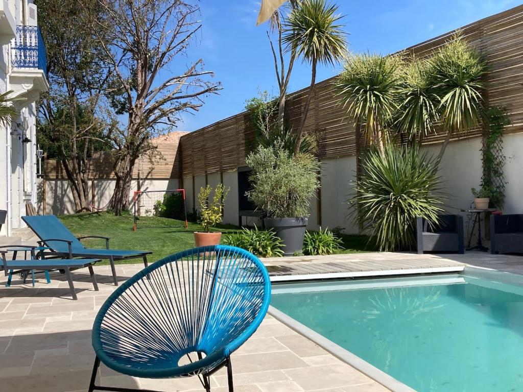 une chaise bleue assise à côté d'une piscine dans l'établissement Great big house, à Saint-Paul-lès-Dax