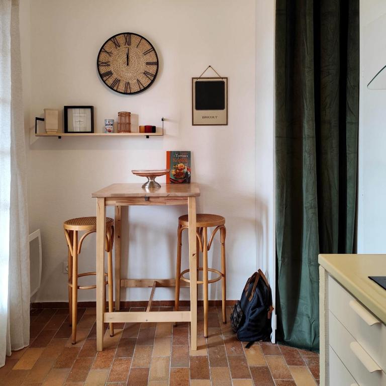 une table et des chaises dans une cuisine avec une horloge murale dans l'établissement Appartement - Suze la Rousse, à Suze-la-Rousse