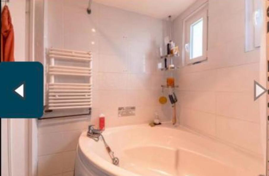 La salle de bains est pourvue d'une baignoire blanche et d'une fenêtre. dans l'établissement Le Havre Saintprio, à Saint-Priest