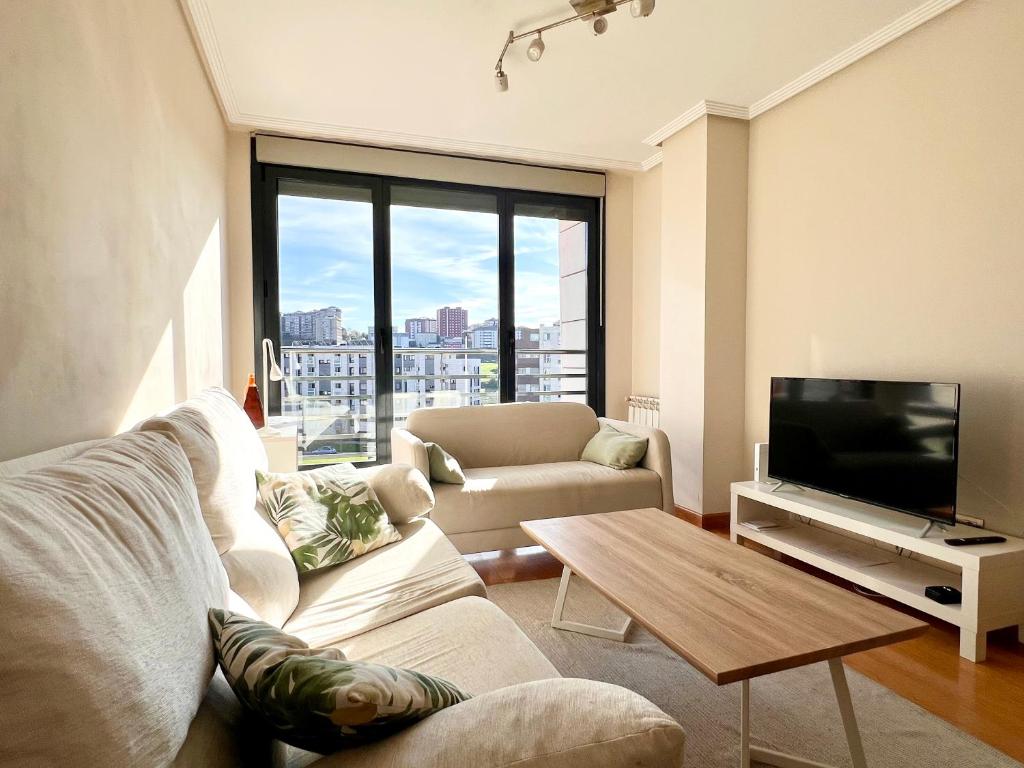 a living room with a couch and a tv at Apartamento Olmeca - Monabri in Santander