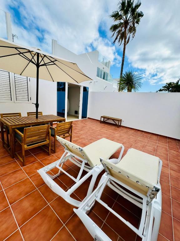 a patio with chairs and a table and an umbrella at Bungalow Timple 2 in Puerto del Carmen