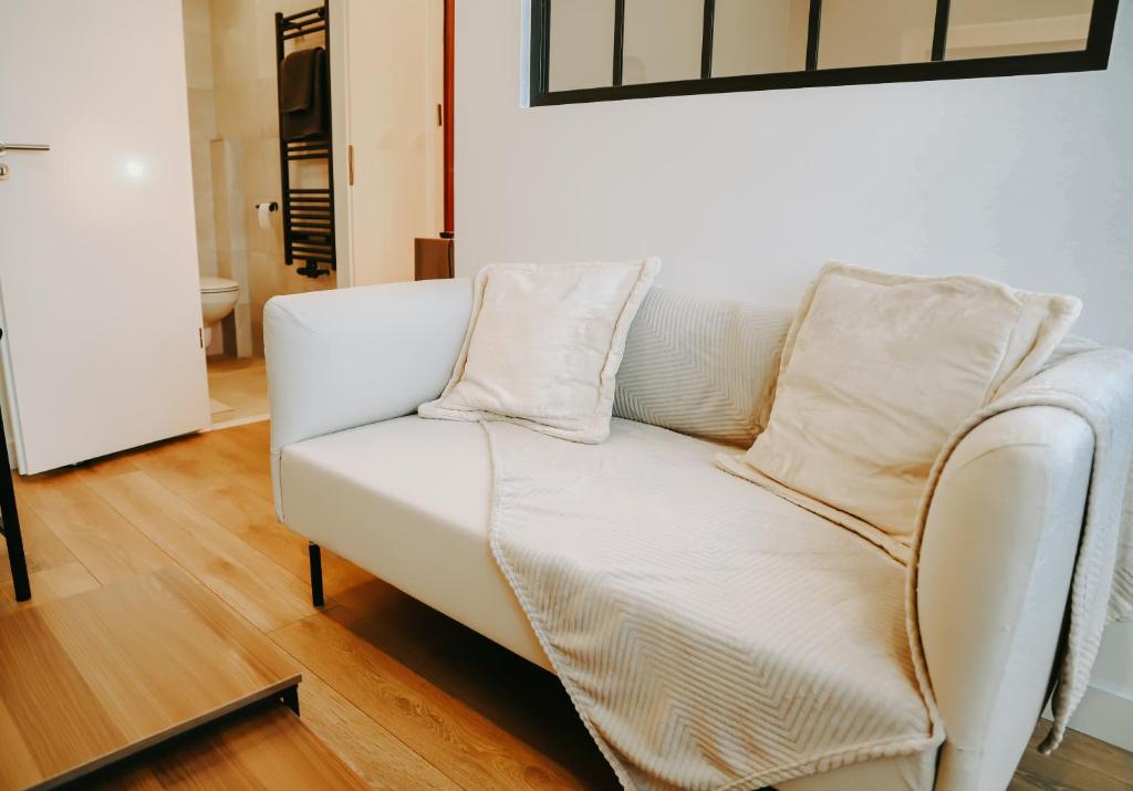 eine weiße Couch mit zwei Kissen darüber in der Unterkunft Appartement cosy proche centre, marché de Noël in Metz