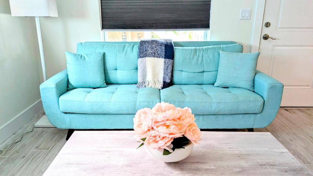 eine blaue Couch in einem Wohnzimmer mit einer Vase aus Blumen in der Unterkunft Sun, Sand, Coastal Haven 2 in Clearwater Beach