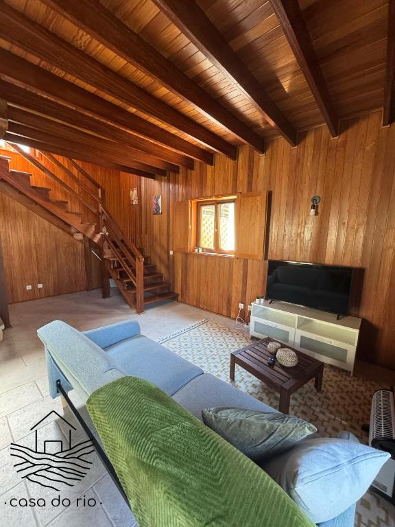 a living room with a blue couch and a television at Casa do Rio, Sever do Vouga in Paradela