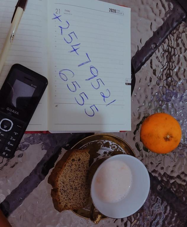 a book and a cell phone next to a plate of bread at Serene Hills Home in Nairobi