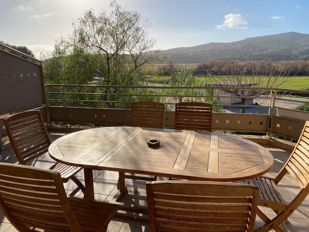 - une table et des chaises en bois sur une terrasse avec vue dans l'établissement Bel appartement 120m2 proche plages et Porto Pollo, à Serra-di-Ferro