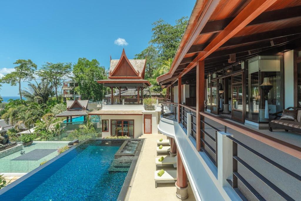 a house with a swimming pool next to a building at Villa Gecko with sea view pool, walk to Beach & Restaurants in Surin Beach
