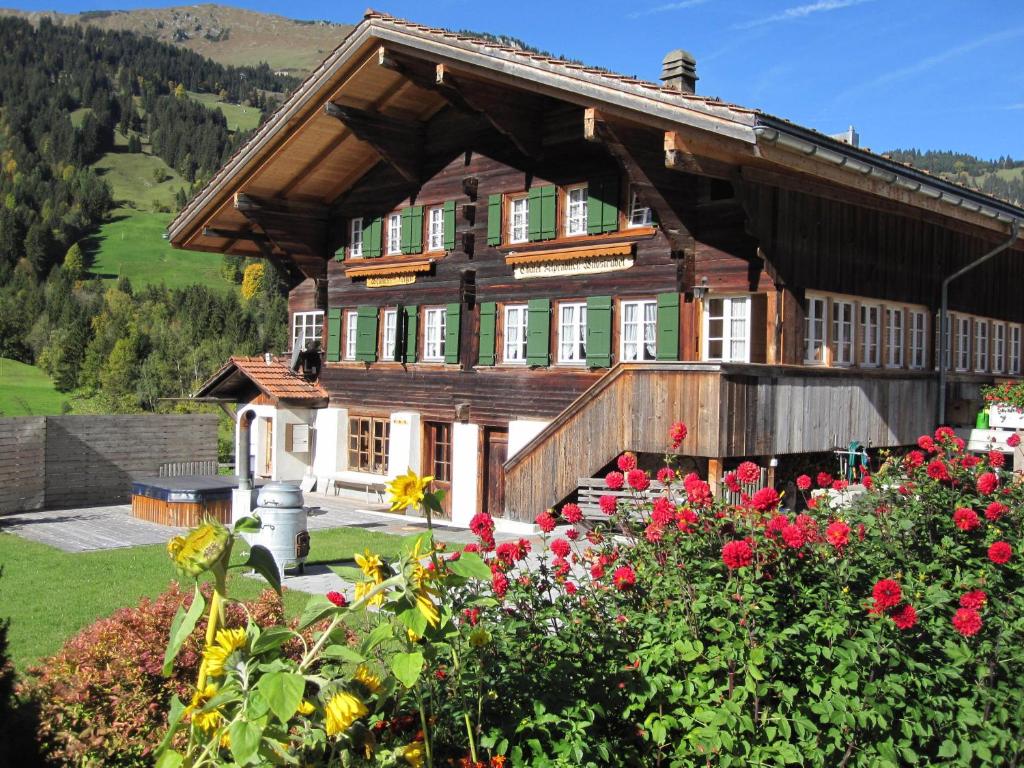 une grande maison en bois avec des fleurs devant elle dans l'établissement Gästehaus Alpenblick Wildstrubel, à Sankt Stephan