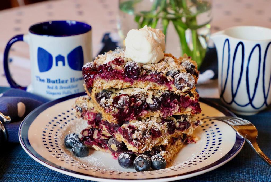 a piece of blueberry cake on a plate with a spoon at The Butler House Bed & Breakfast in Niagara Falls