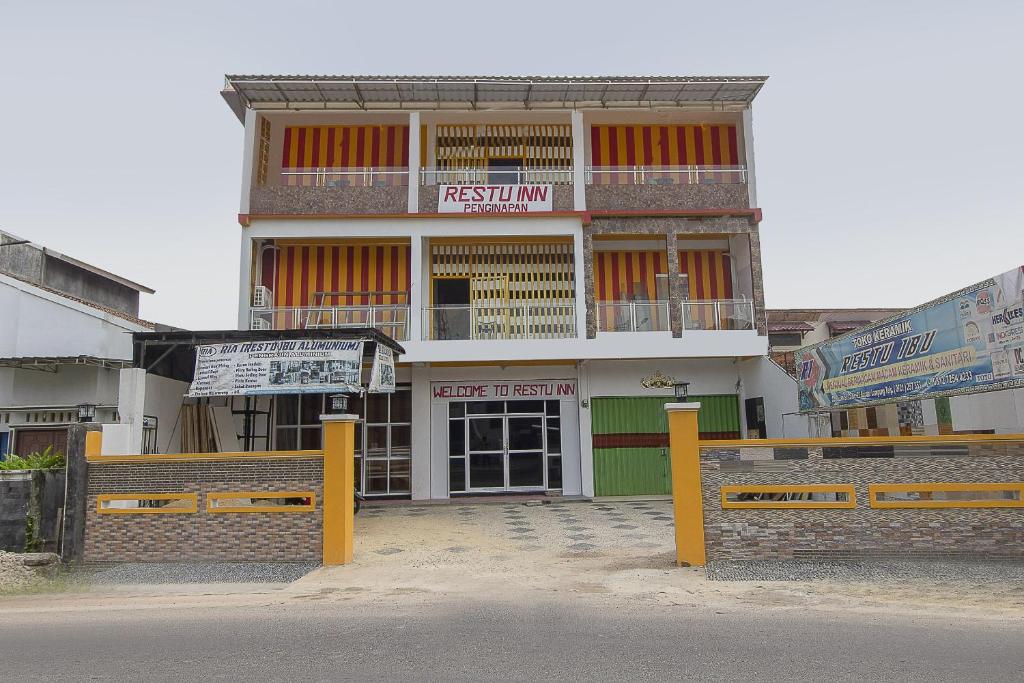 a building with yellow posts in front of it at Hotel O Restu Inn in Lampung