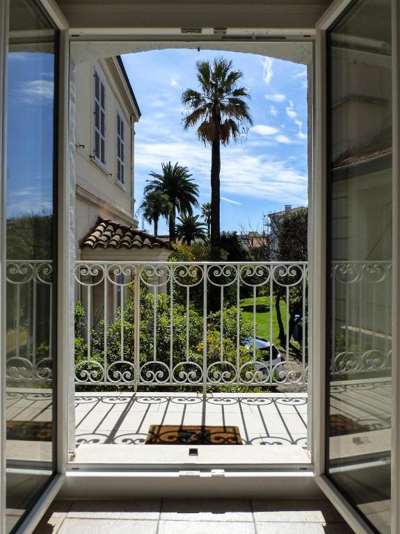 d'une fenêtre donnant sur un balcon avec un palmier. dans l'établissement Villa Divona - central gem with sunset balcony & pool, à Cannes
