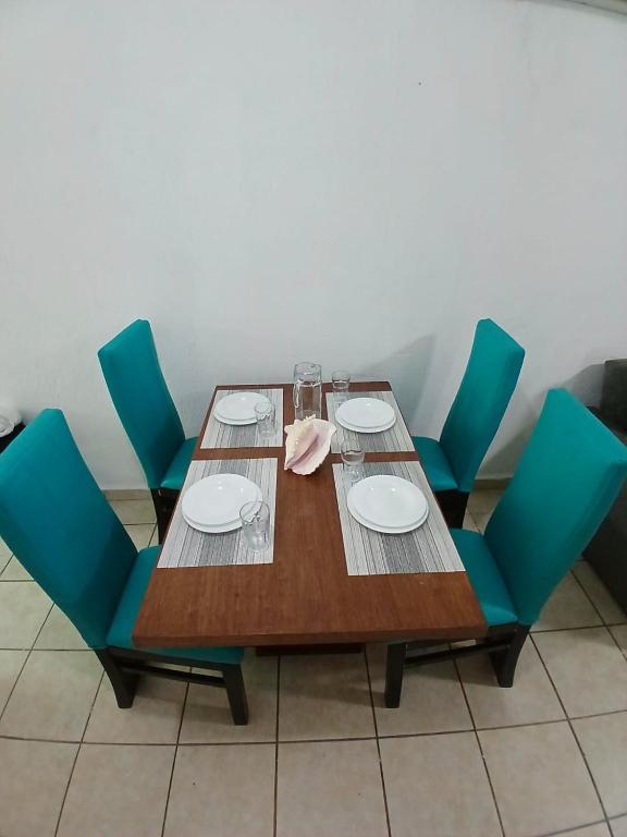 a wooden table with blue chairs and plates on it at Autentico y Lindo Departamento in Puerto Vallarta