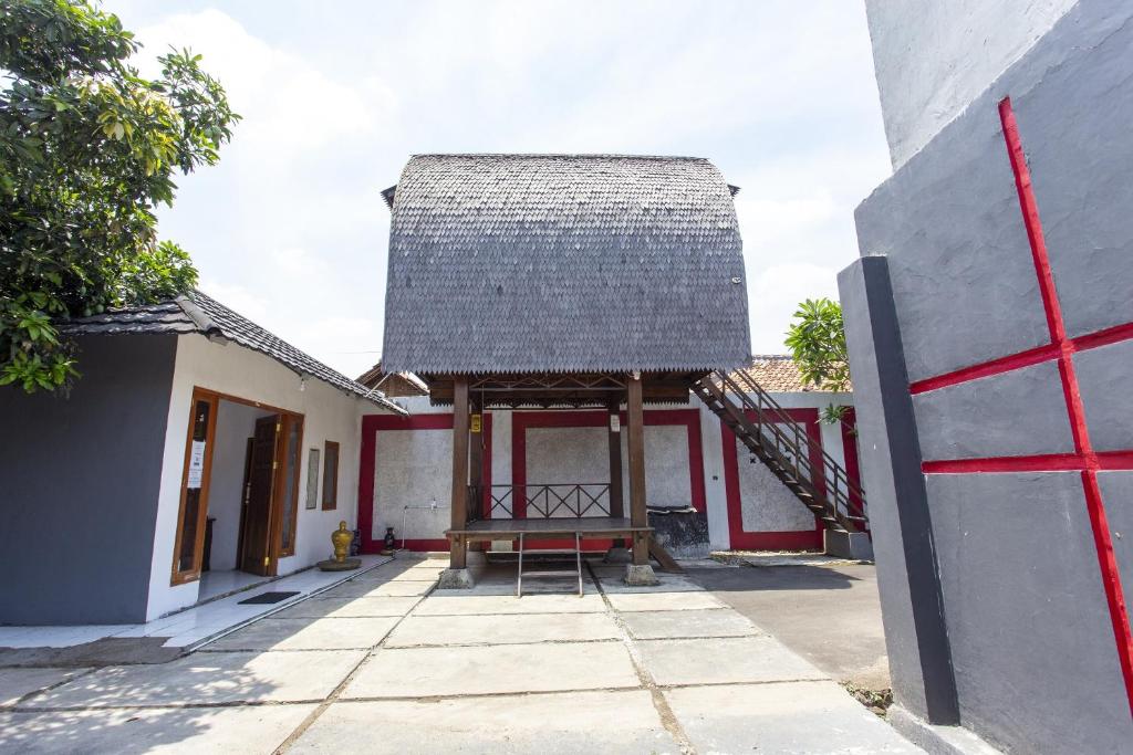 a building with a thatched roof and a porch at Hotel O near Metropolitan Mall formerly Sakura Home Stay in Kaum