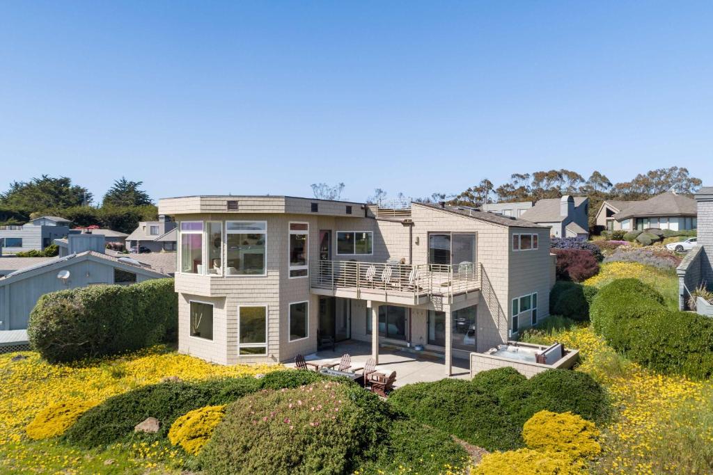 a large house on top of a field of flowers at Breathtaking Views of the Pacific Ocean Rooftop Balcony Gourmet Kitchen and Hot Tub overlooking Golf Course in Bodega Bay