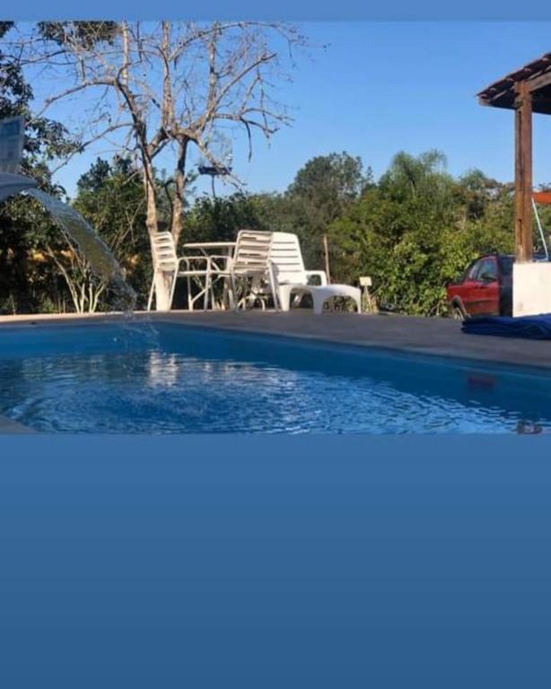 a swimming pool with chairs and a table and a car at casa rosa in Cotia