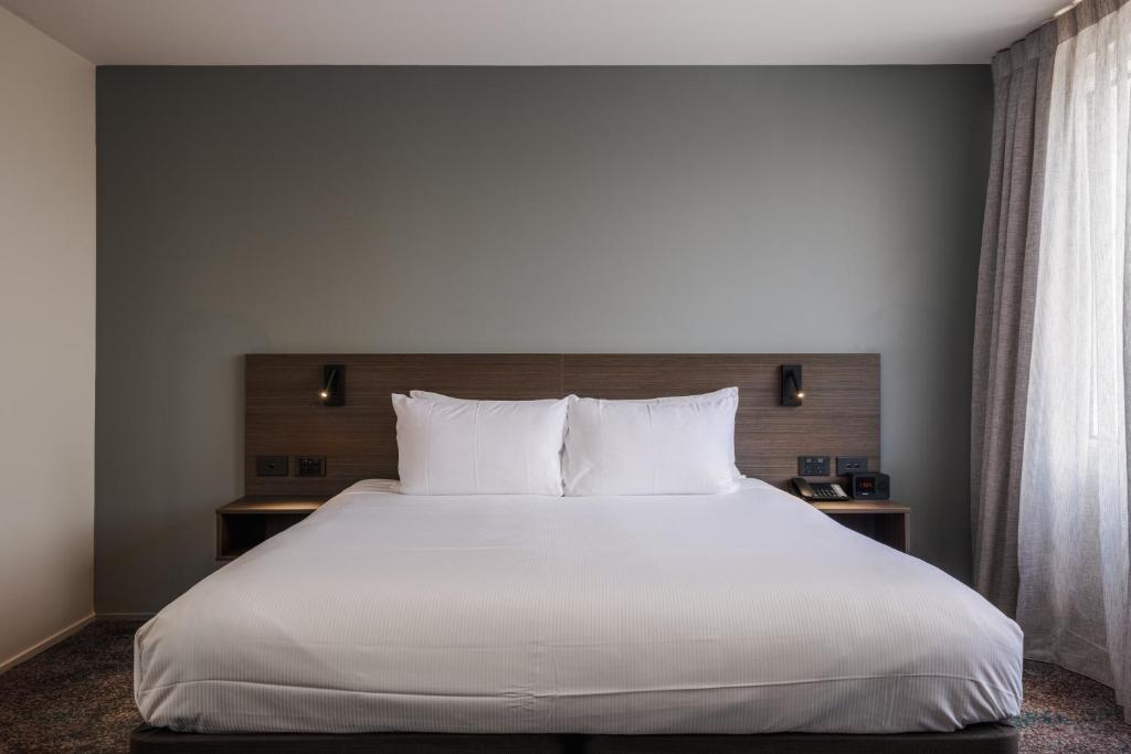 a bedroom with a large bed with white sheets and pillows at Heartland Hotel Auckland Airport in Auckland