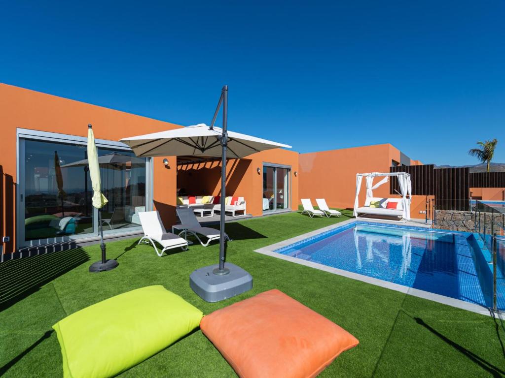 a backyard with a swimming pool and an umbrella at Chalet in Maspalomas with Heated Pool in San Bartolomé de Tirajana