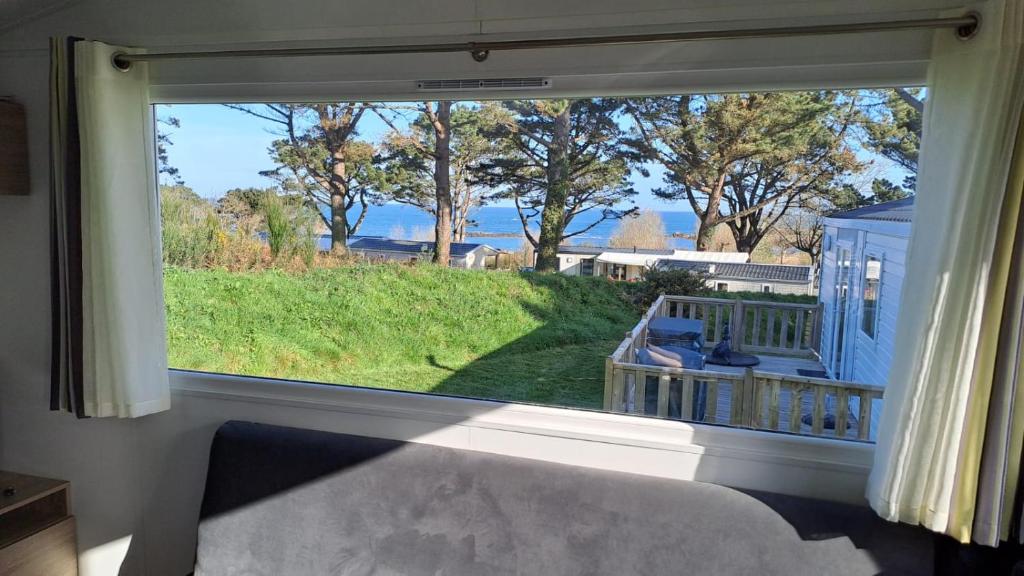 d'une grande fenêtre avec vue sur la cour. dans l'établissement Mobil-home convivial avec vue sur mer - Pleubian, à Pleubian